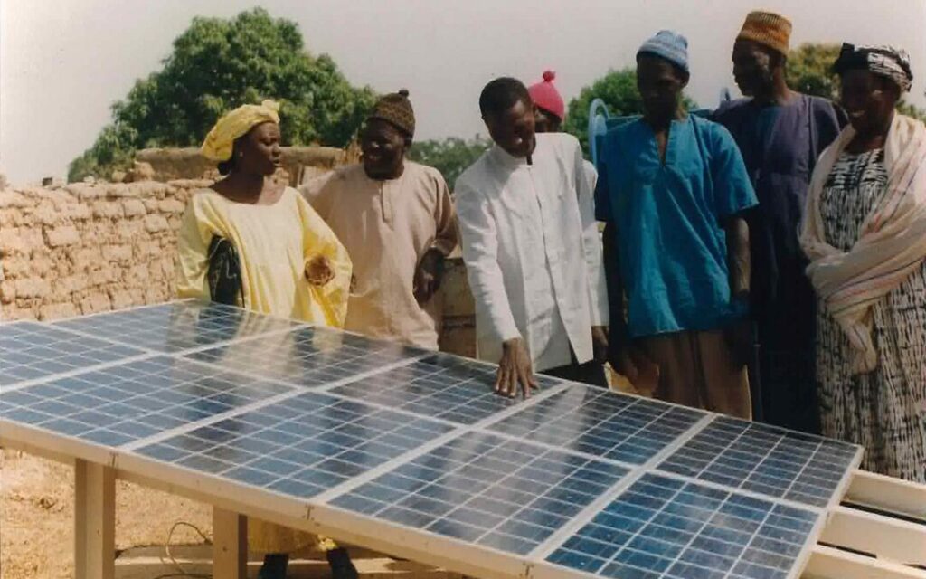 Installation de panneaux solaires dans un village en développement, illustrant les efforts pour une transition écologique inclusive.