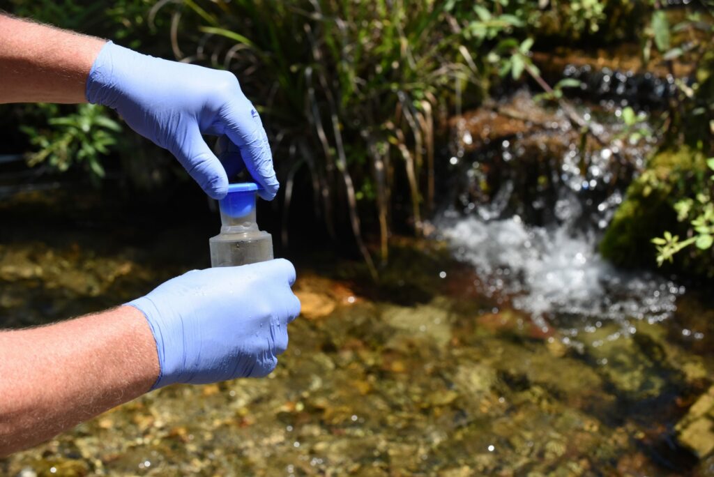 Prélèvement d’eau pour analyse de pesticides dans une zone rurale agricole en France.