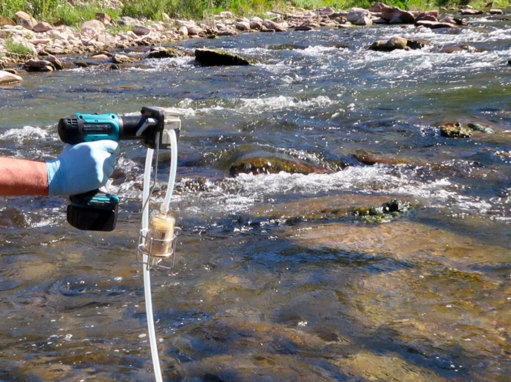 Prélèvement d'eau destiné à une analyse d'ADN environnemental dans une rivière.